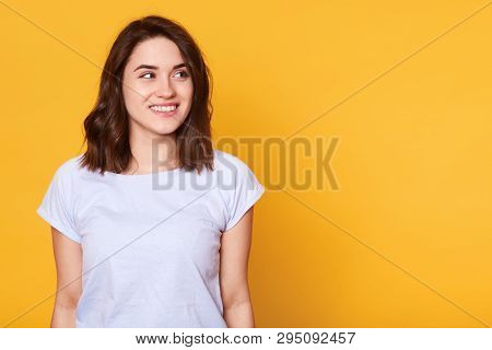 Portrait Of Attractive Beautiful Fair Haired Young Lady Posing Isolated Over Yellow Background, Look