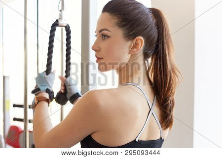 Profile Of Athletic Young Woman Works Out On Training Apparatus In Gym Class, Looks Aside, Trains He