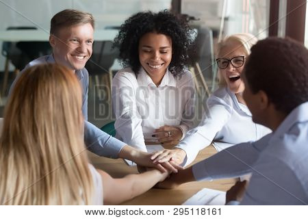 Happy Multi Ethnic Employees Stacking Hands Engaged In Team Building
