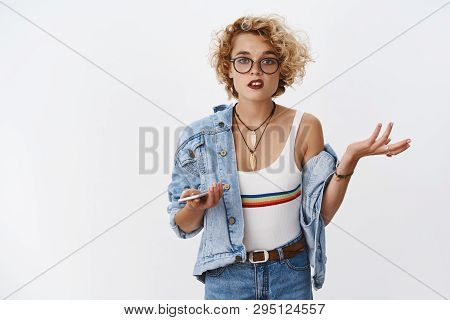 I Not Get It, What I Did Wrong. Portrait Of Confused And Clueless Girl Raising Hand In Dismay And Qu