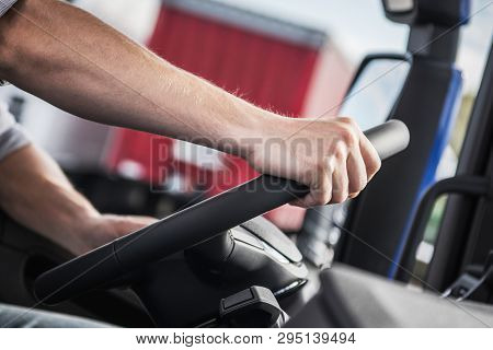 Hand On Truck Steering Wheel. Caucasian Trucker On The Road. Closeup Photo. Transportation Industry.