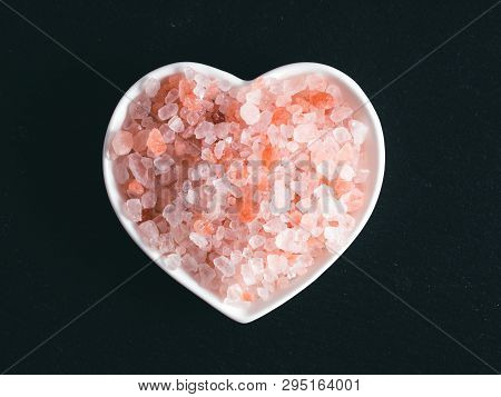 Himalayan Pink Salt In Hearth-shape Bowl On Black Stone Background. Copy Space