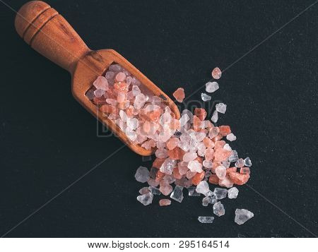 Himalayan Pink Salt In Wooden Scoop On Black Stone Background. Copy Space