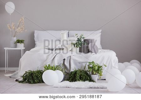 Urban Jungle And White Balloons In Fashionable Bedroom Interior With Large Bed With Cozy Bedding, Re