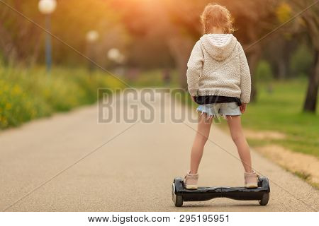 Child On Hoverboard. Kids Riding Scooter In Summer Park. Balance Board For Children. Electric Self B