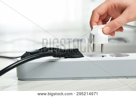 Woman Inserting Power Plug Into Extension Cord On Floor Indoors, Closeup With Space For Text. Electr