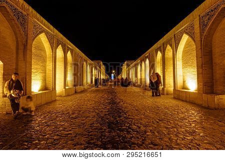 Isfahan, Iran - May 7, 2015: People Walking And Socializing On The Ancient Khaju Bridge By Night.