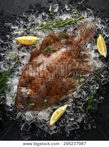Raw Lemon Sole Fish On Ice With Herbs And Lemon Wedges