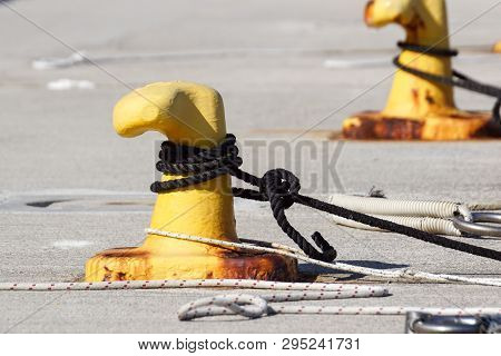 A Mooring Bollard Entwined With A Mooring Rope. Moored Ships At The Port Quay