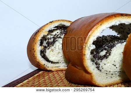 Poppy Seed Bun, Cut Into Several Pieces, Placed On A White Background