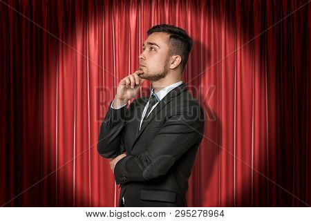Close-up Of Young Businessman Standing In Half-turn Looking Away And Up, With Hand On Chin, Lit Up B