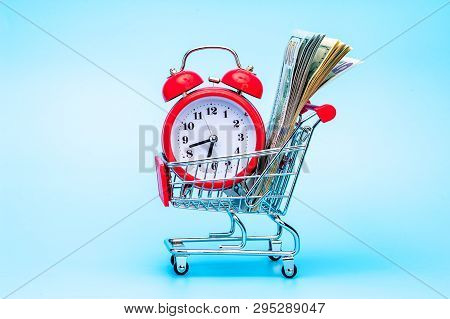 Red Retro Alarm Clock And Dollar Bills In Shopping Cart On Blue Background. Shopping Time, Market, C
