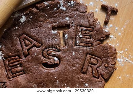 Cut Cookies From Raw Chocolate Dough On A Wooden Table With Letters. Cooking Traditional Easter Bisc