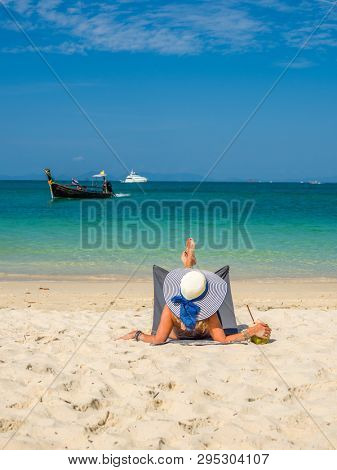 Woman enjoying her holidays on a transat at the tropical beach in Thailand - UNRETOUCHED body.