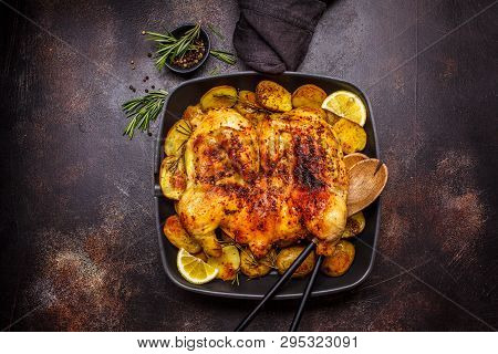 Fried Whole Tabaka Chicken With Potatoes In A Grill Pan, Top View, Dark Background.