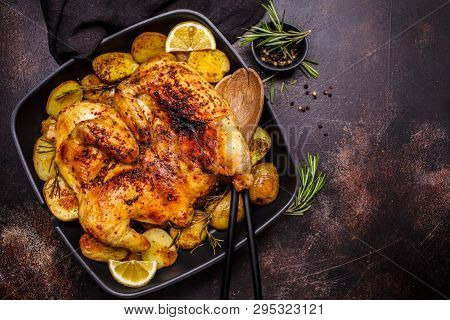 Fried Whole Tabaka Chicken With Potatoes In A Grill Pan, Top View, Dark Background.