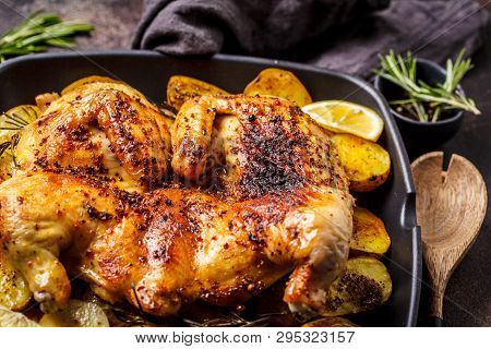 Fried Whole Tabaka Chicken With Potatoes In A Grill Pan, Dark Background.