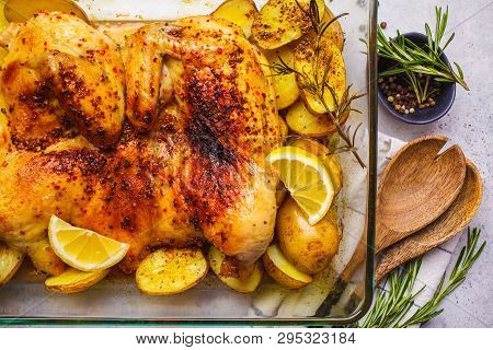 Roasted Whole Tabaka Chicken With Potatoes In A Glass Oven Dish, Top View, White Background.