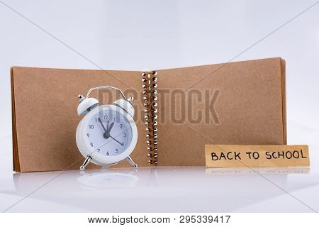 Brown Color Notebook And Alarm Clock  With The Titile Back To School