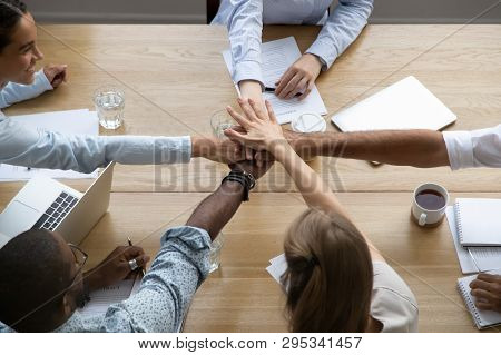 Team People Stacking Hands Together Over Table Engaged In Teambuilding