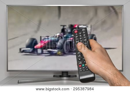 Formula One Racing On Tv And Human Hand With Tv Remote Controller