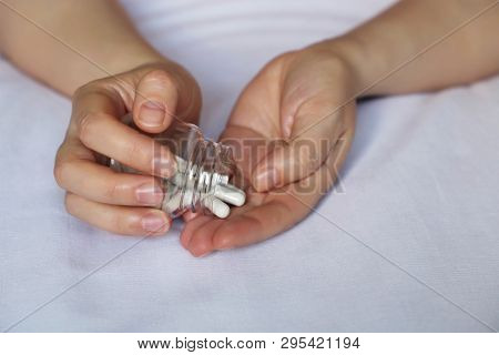 Pills In Female Hands, Woman With Bottle Of Capsules Lays On The Bed. Concept Of Medical Clinic, Pha