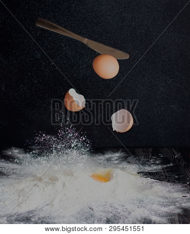Eggs Are Broken By A Knife And Fall Into Flour On A Black Background.