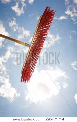 Broom Red Sweeping Brush Against Blue And White Cloudy Sky. Household Obejcts Concept.