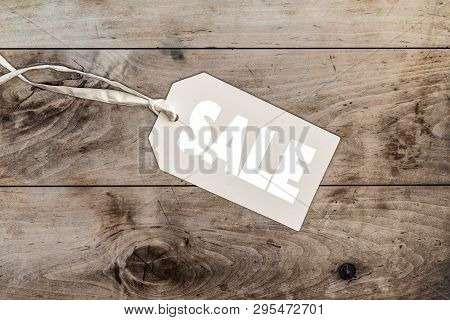 Word Sale On Cardboard Label Price Tag With Thread Binding Against Wooden Table