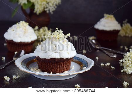 Chocolate Capcakes With Vanilla Cream Sprinkled With White Chocolate And Elderberry Flowers. Vintage