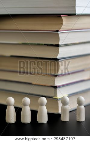 Figures Of People And A Stack Of Books On A Black Background. The Concept Of Education. The Problem 