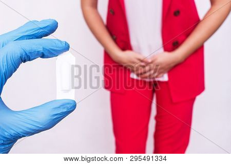 Doctor Holds Vaginal Suppository Suppository Against The Background Of A Girl Who Has Pain And Infla