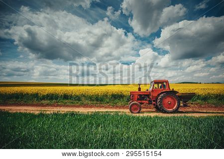 Red Tractor In A Field And Dramatic Clouds