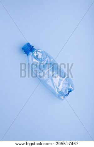 Squashed plastic bottle on vivid bright blue background. Plastic utilisation concept. Ecological problem, global environment.