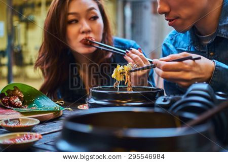 Young Chainese Couple Trying Asian Food At First Time. Couple Is Siting At Cafe Outside. They Have C