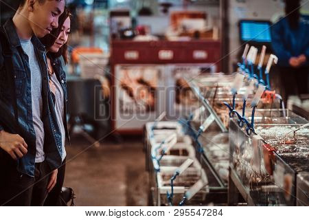 Romantic Asian Couple Looking For Something Special At Seafood Chainese Market. They Are Curious And
