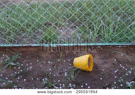 Yellow Flowerpot Near A Fencing In Cloudy Day