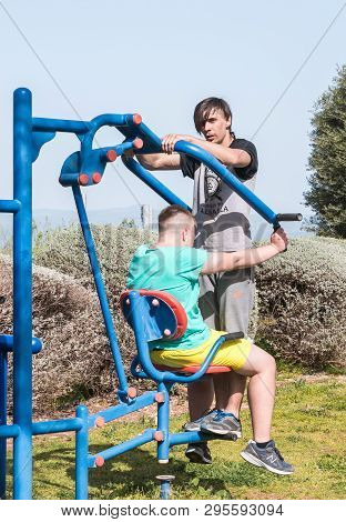 Safed, Israel, April 13, 2019 : Two Athletes Perform Paired Exercises On Outdoor Public Exercise Mac