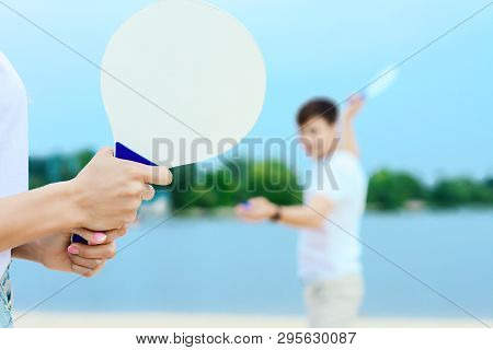 Young Smiling Woman In Light Clothes Is Holding White Racket And Ball In Her Hands. Cheerful Female 