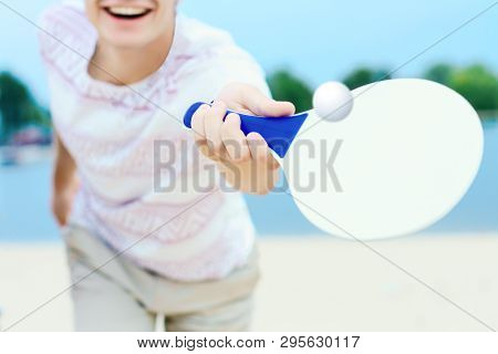 Young Smiling Woman In Light Clothes Is Holding White Racket And Ball In Her Hands. Cheerful Female 