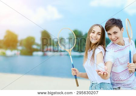 Young Smiling Woman In Light Clothes Is Holding White Racket And Ball In Her Hands. Cheerful Female 