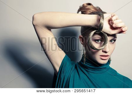 A Beautiful Young Blonde In Blue Dress Wearing Wristbands Over Gray Background. Studio Shot