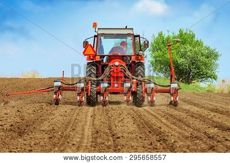 Unrecognizable Farmer Is Driving Tractor With Mounted Crop Seeder And Planting Corn Seed In Field