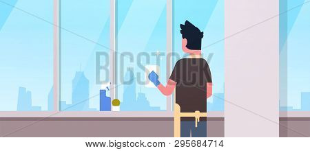 Man In Gloves And Apron Cleaning Windows With Rag Cleaner Spray Rear View Guy Doing Housework Concep