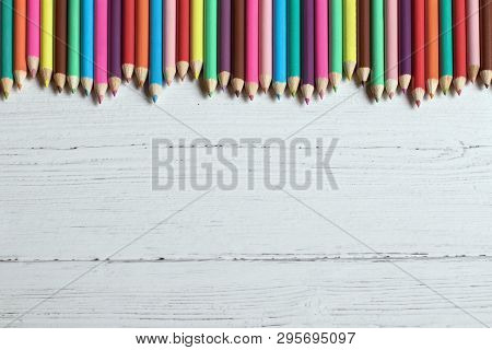 Border Of Coloured Pencils On A Wooden Background, With Copy Space