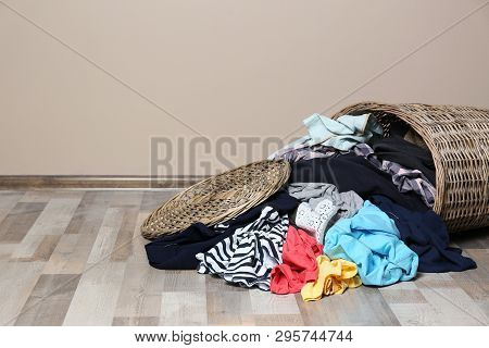 Dirty Clothes Scattered From Laundry Basket On Floor Indoors. Space For Text