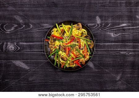 Appetizing Stir Fried Noodles With Garlic Sprouts, Mushrooms, Red Pepper And Chicken Meat On A Black