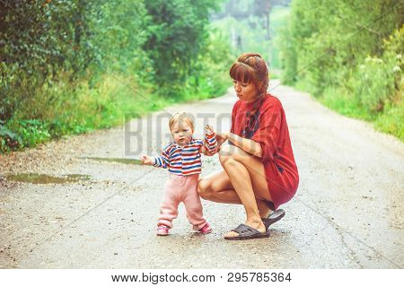 The Child Learns To Walk In The Park Barefoot On The Grass
