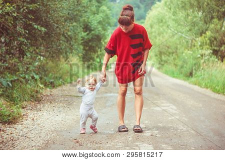 The Child Learns To Walk In The Park Barefoot On The Grass