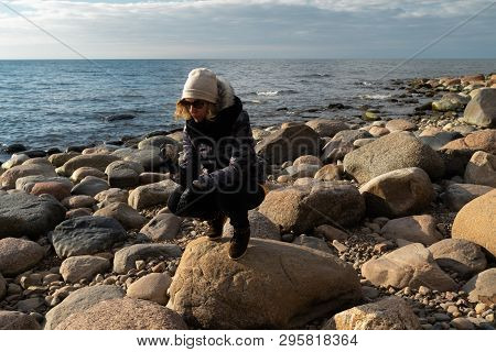 Young Archaeologist On A Boulder Beach Looking For Exotic Rocks On A Coastline Of A Baltic Sea